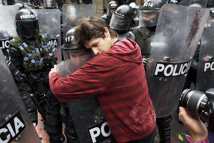 Page by Andrew Boyd  Bogota, Colombia A demonstrator embraces a riot police officer during a student protest against government plans to reform higher education.