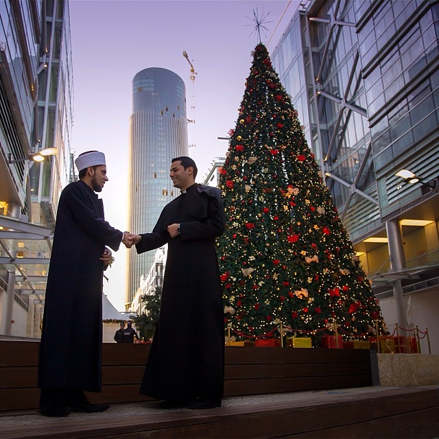 islamic imam and christian priest shaking hands
